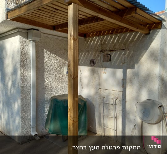 פרגולה מעץ עם גג מתכת ליד קיר חיצוני
